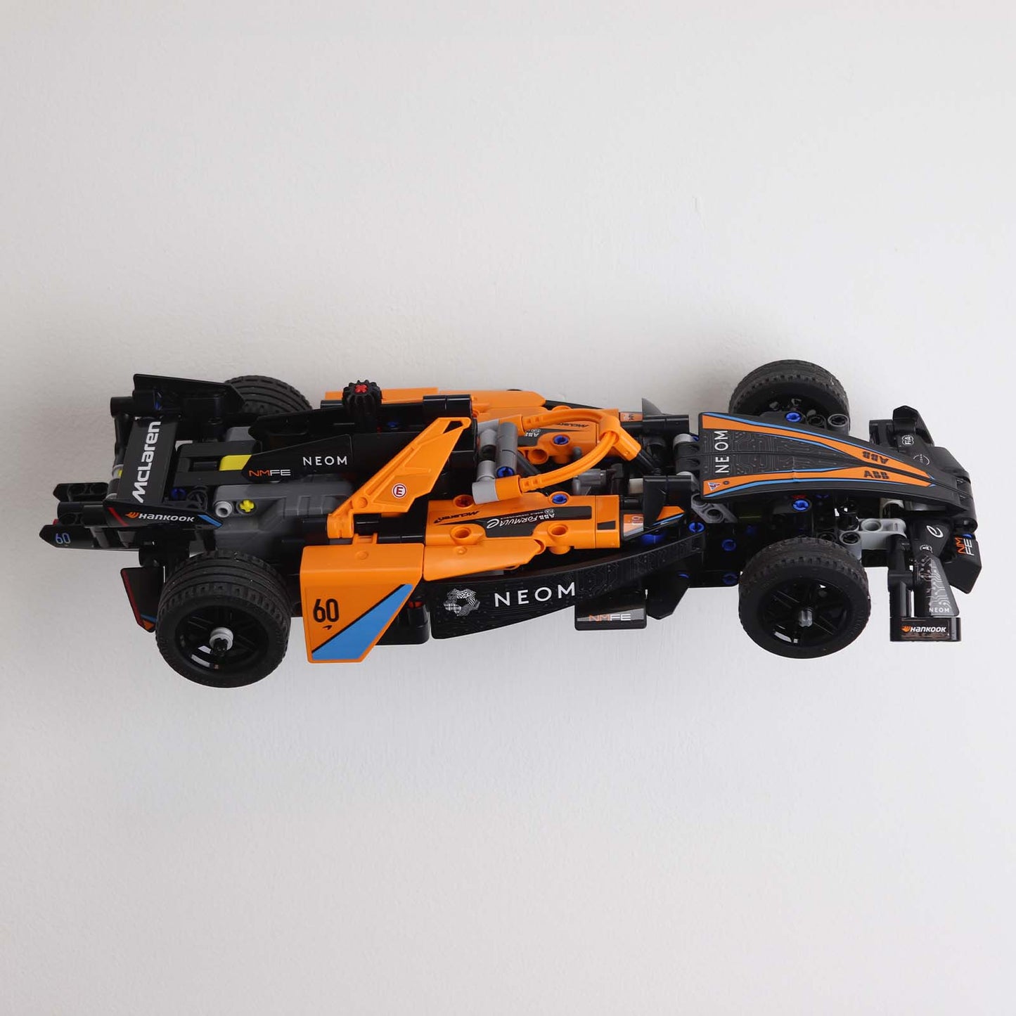 Wall display mount holding LEGO® McLaren Formula E (42169) model, displaying the car at an angled position on the wall for an attractive presentation.
