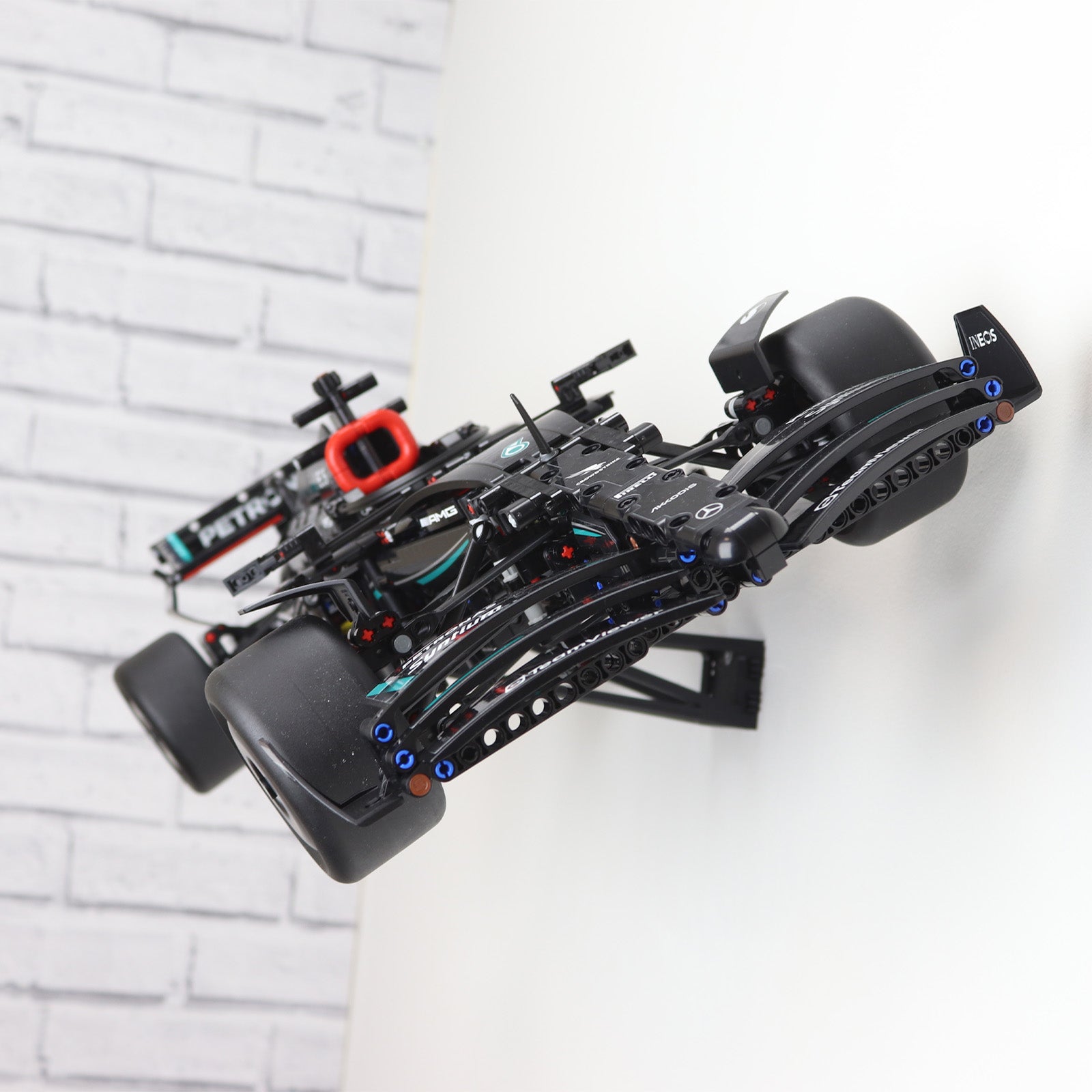 Wall display mount holding LEGO® Technic Mercedes F1 Car (42171) model, showcasing the car at an angled position on the wall for an eye-catching presentation.