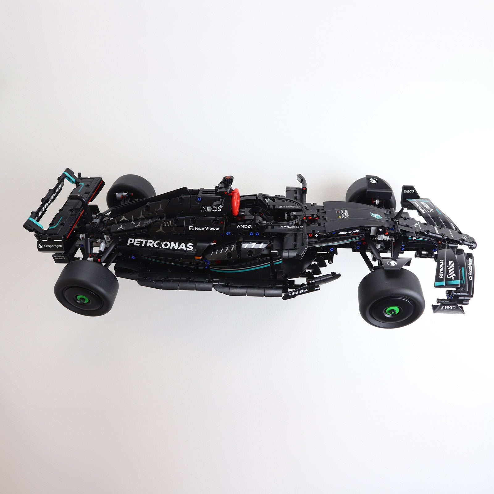 Wall display mount holding LEGO® Technic Mercedes F1 Car (42171) model, showcasing the car at an angled position on the wall for an eye-catching presentation.