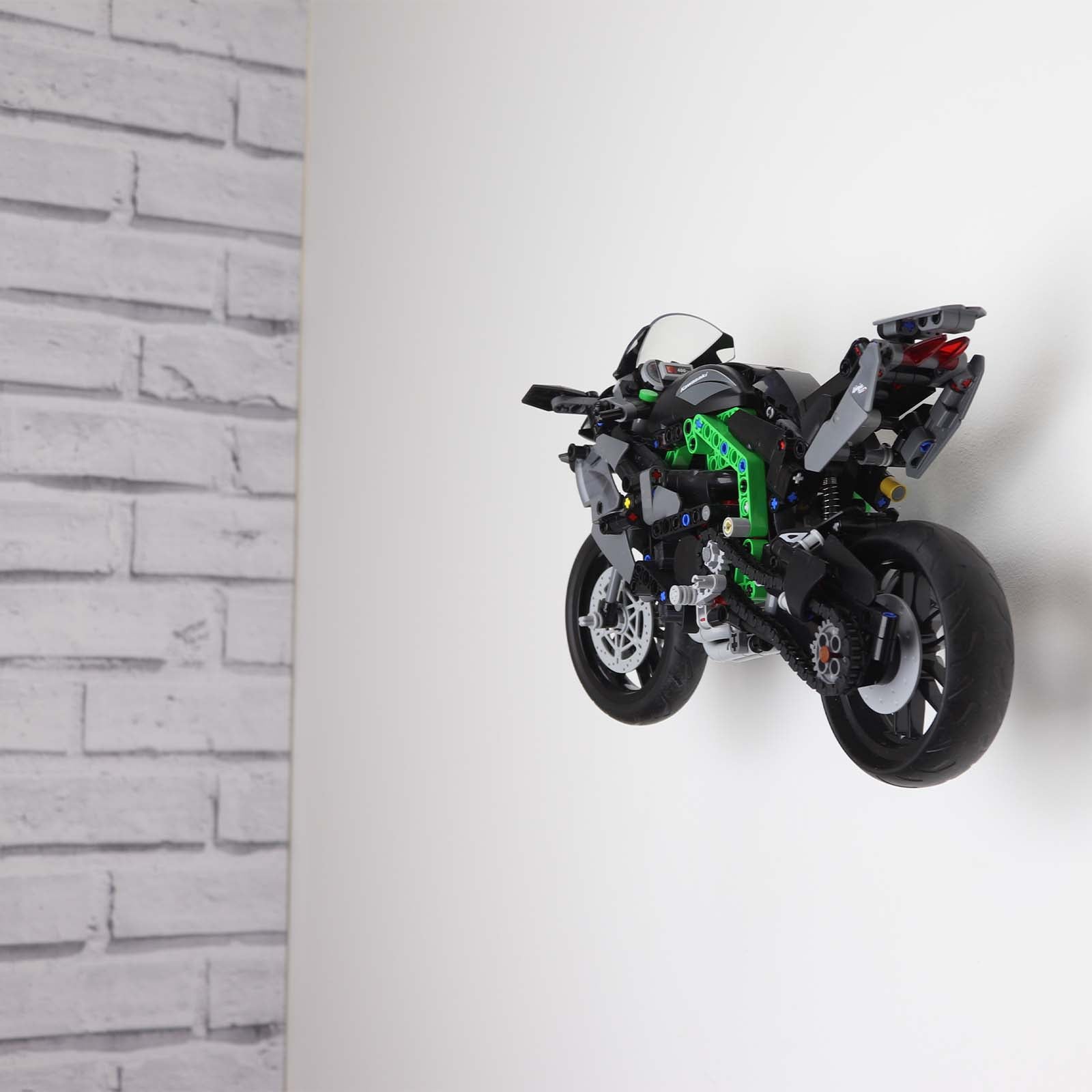 Wall display mount holding LEGO® Kawasaki Ninja Motorcycle (42170) model, displaying the motorcycle at an angled position on the wall for an attractive presentation.
