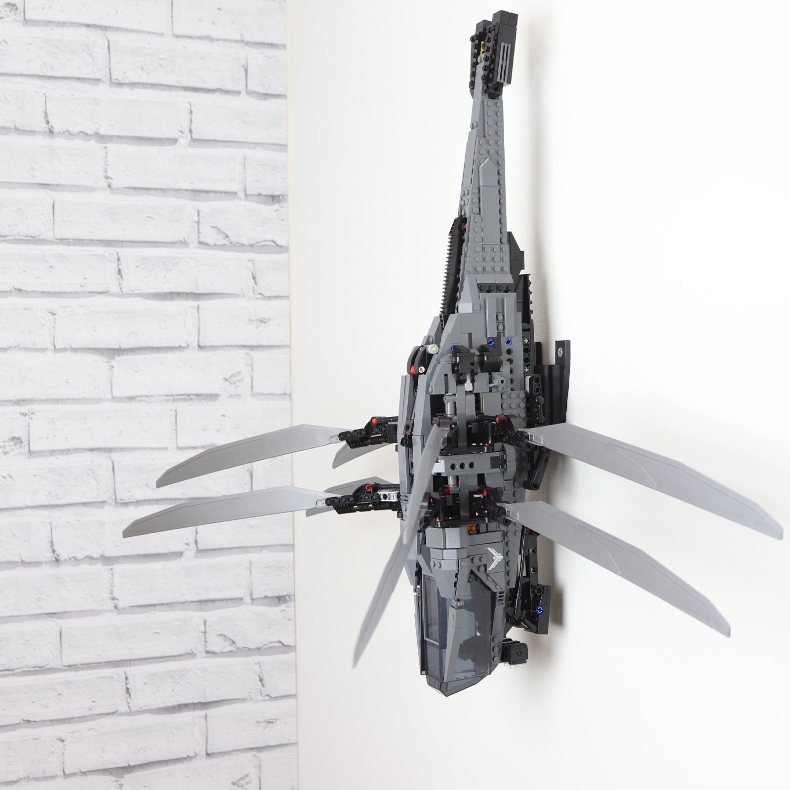 Vertical wall mount display stand holding LEGO® Dune Atreides Royal Ornithopter 10327 model, presenting the aircraft at a dynamic angle on the wall.
