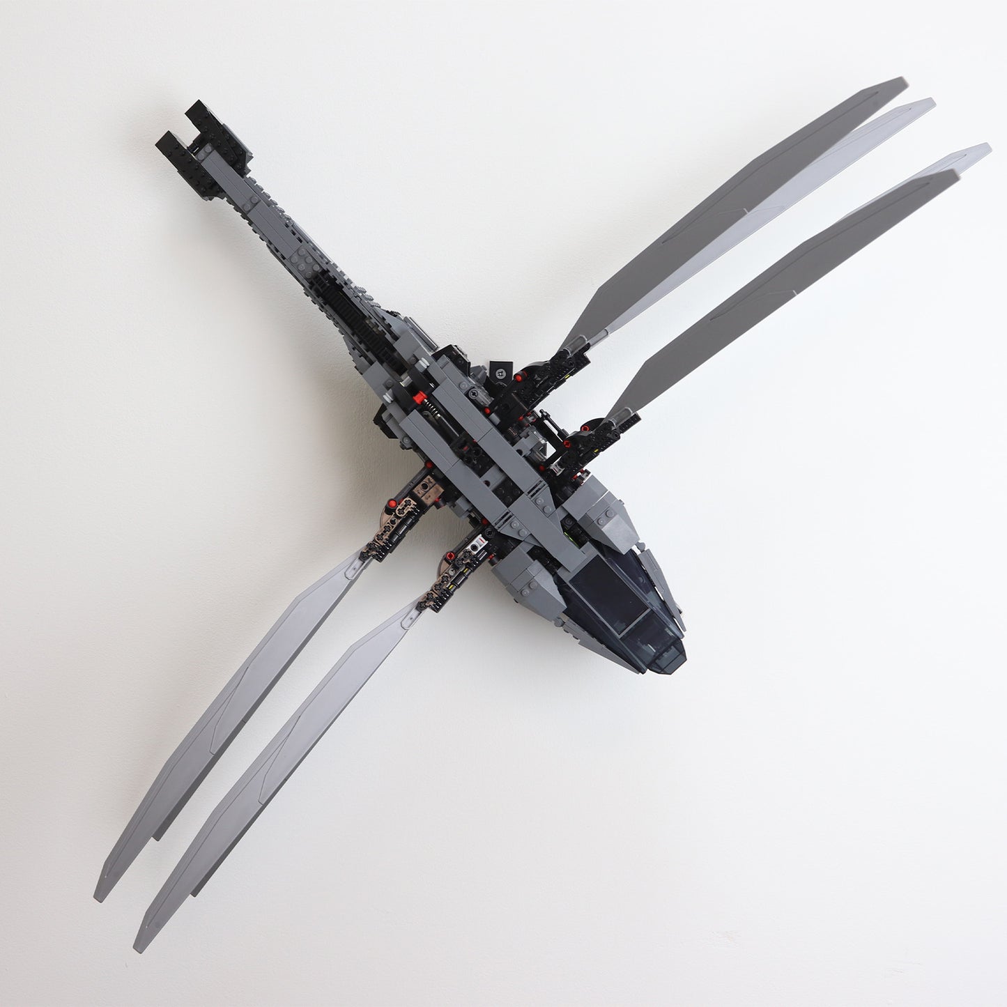 Vertical wall mount display stand holding LEGO® Dune Atreides Royal Ornithopter 10327 model, presenting the aircraft at a dynamic angle on the wall.
