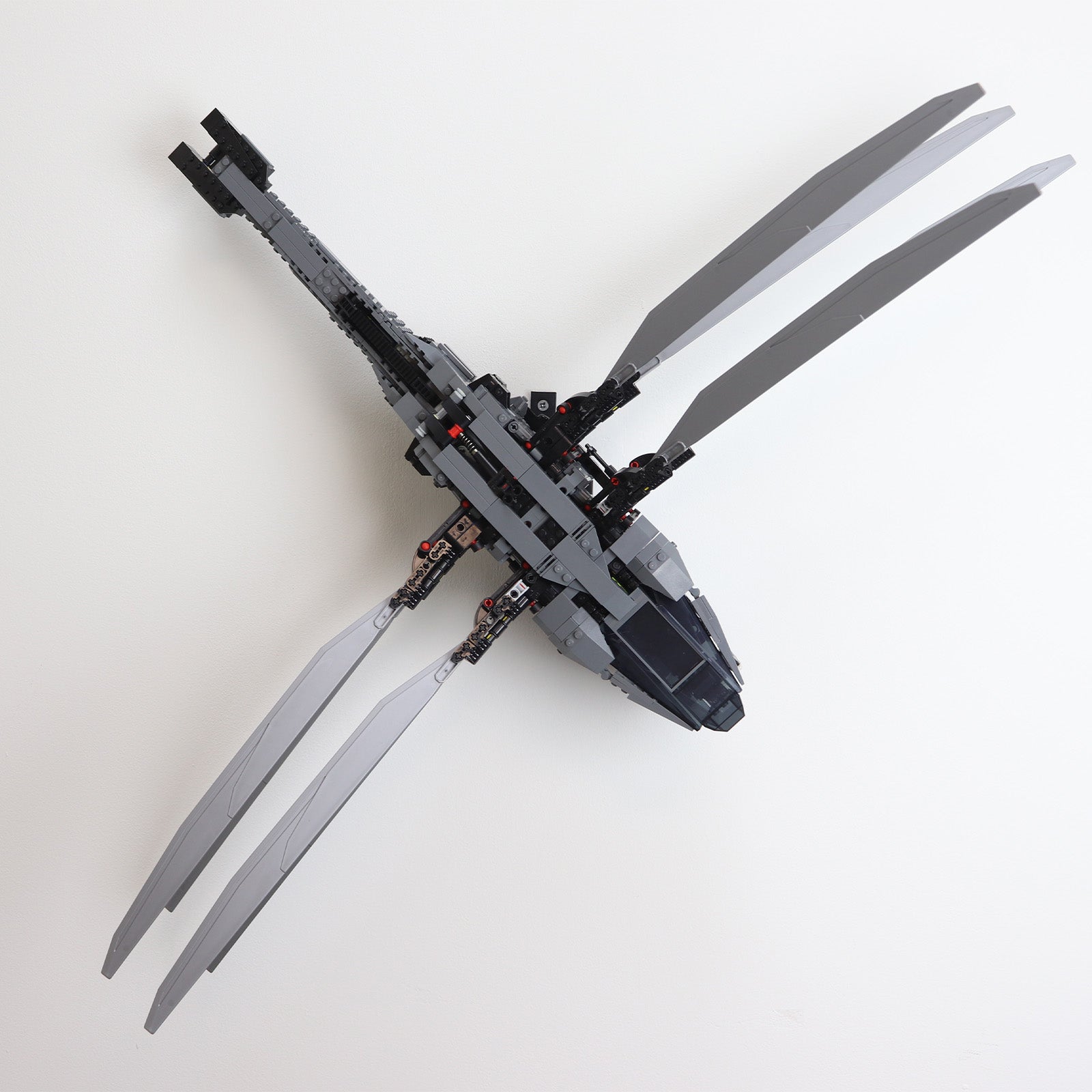 Vertical wall mount display stand holding LEGO® Dune Atreides Royal Ornithopter 10327 model, presenting the aircraft at a dynamic angle on the wall.
