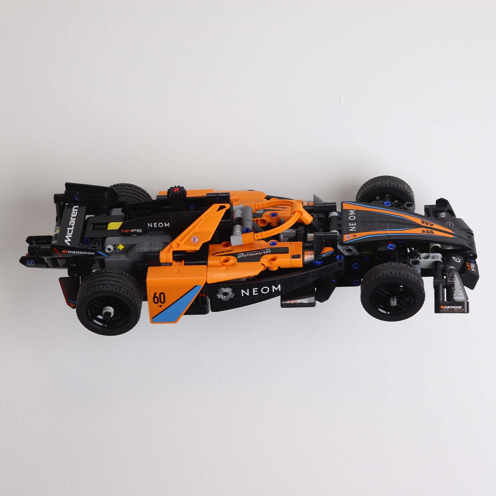 Wall display mount holding LEGO® McLaren Formula E (42169) model, displaying the car at an angled position on the wall for an attractive presentation.
