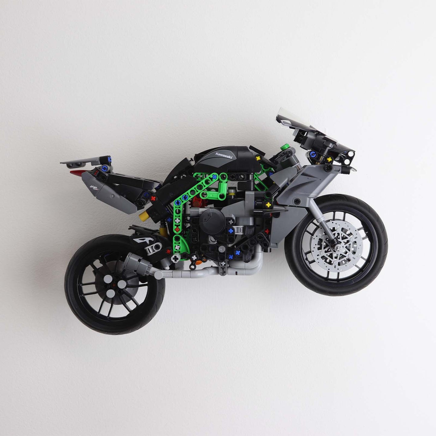 Wall display mount holding LEGO® Kawasaki Ninja Motorcycle (42170) model, displaying the motorcycle at an angled position on the wall for an attractive presentation.
