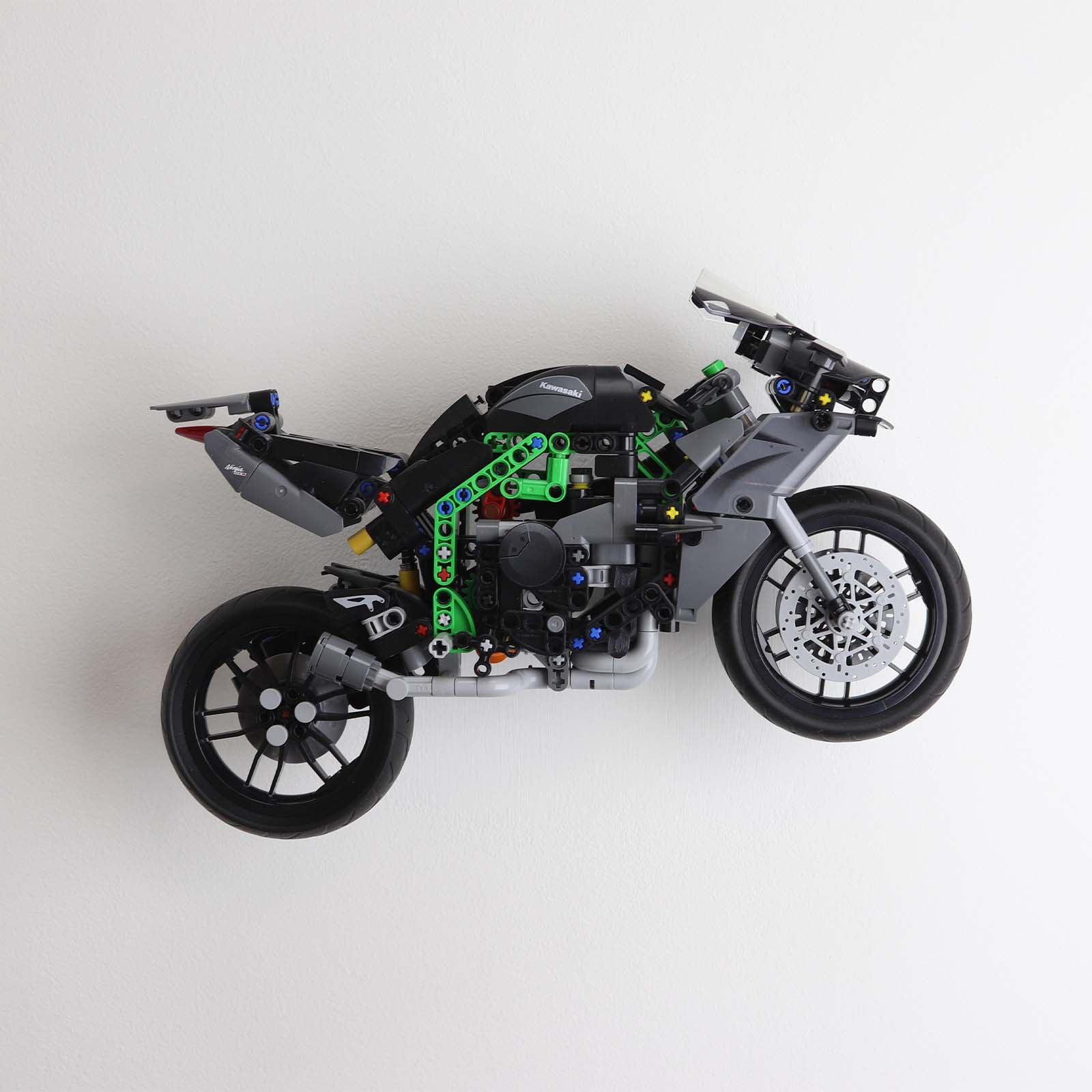 Wall display mount holding LEGO® Kawasaki Ninja Motorcycle (42170) model, displaying the motorcycle at an angled position on the wall for an attractive presentation.
