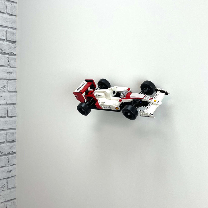 Wall display mount holding LEGO® McLaren MP4/4 & Ayrton Senna (10330) model, showcasing the car at an angled position on the wall for an eye-catching display.
