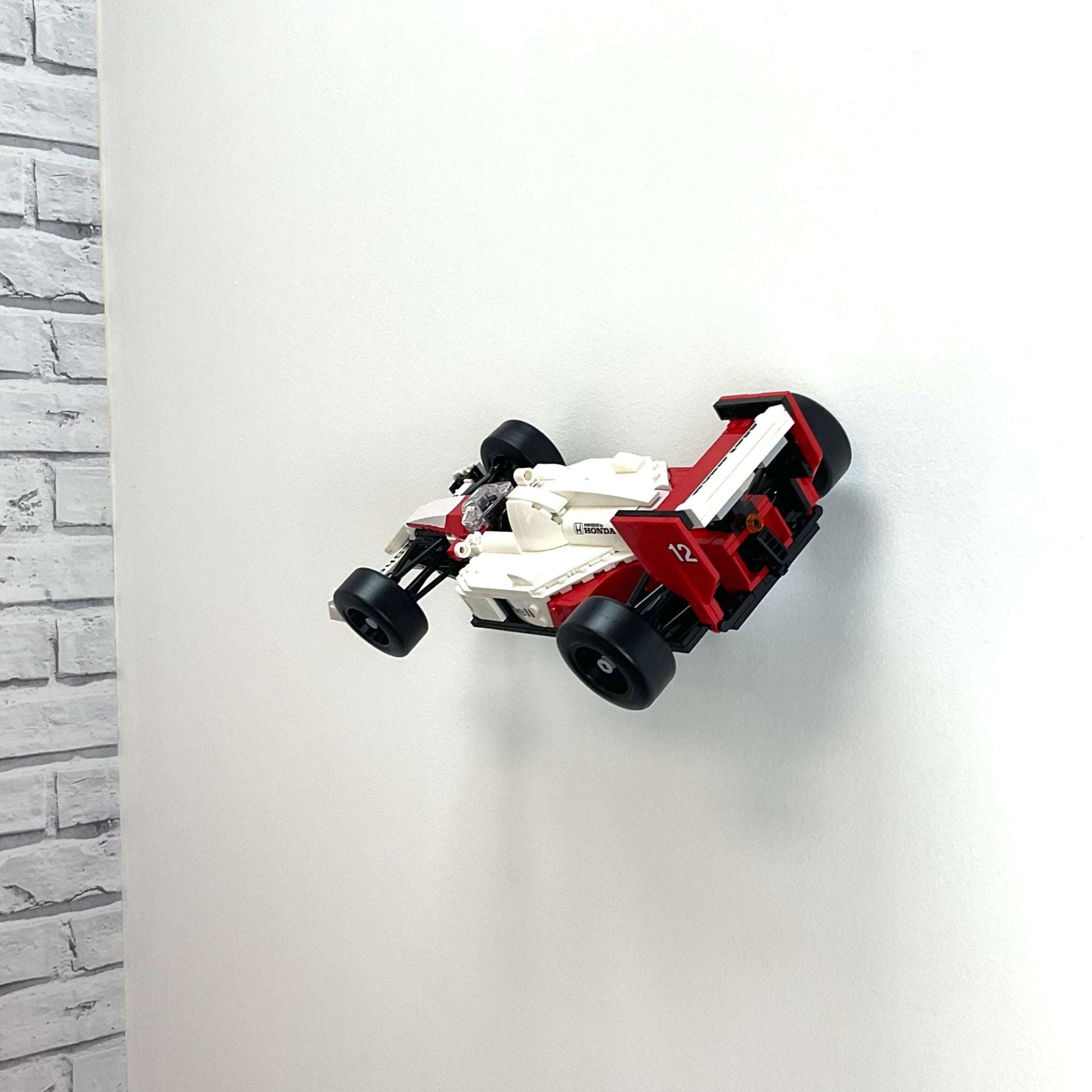 Wall display mount holding LEGO® McLaren MP4/4 & Ayrton Senna (10330) model, showcasing the car at an angled position on the wall for an eye-catching display.
