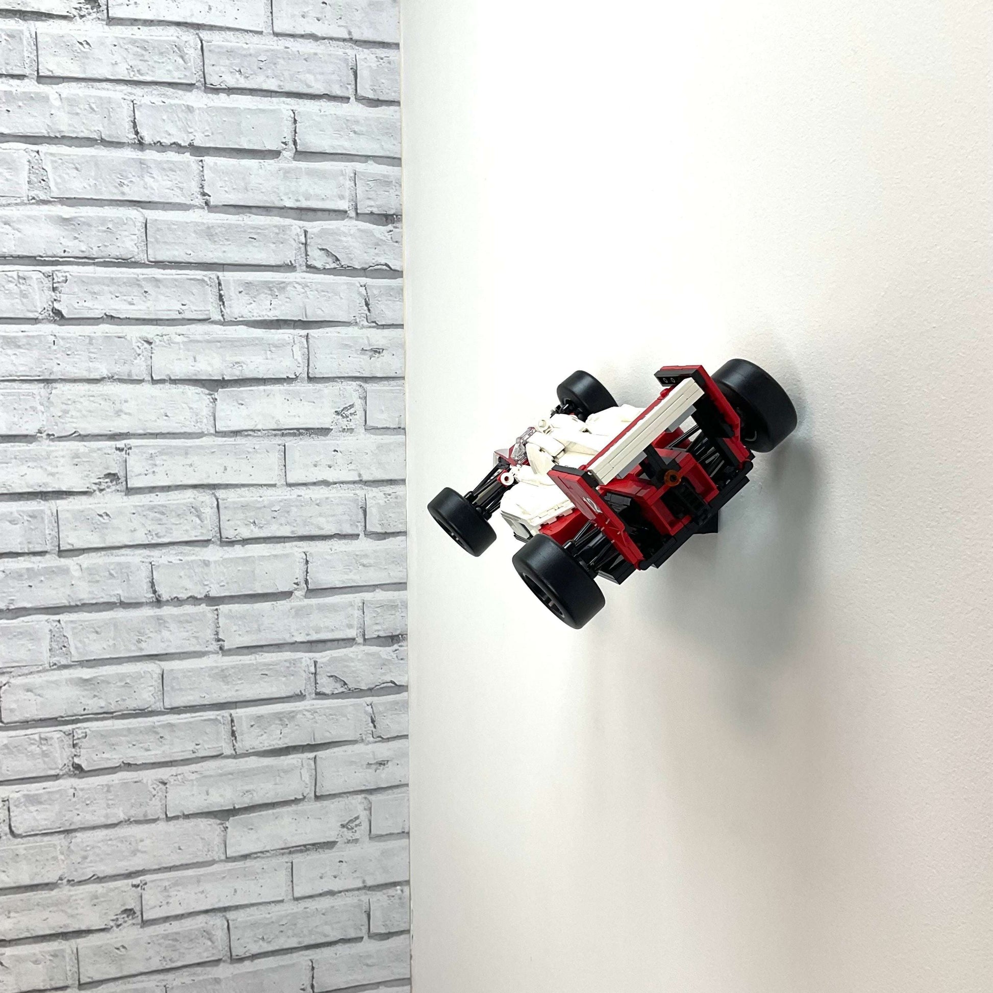 Wall display mount holding LEGO® McLaren MP4/4 & Ayrton Senna (10330) model, showcasing the car at an angled position on the wall for an eye-catching display.
