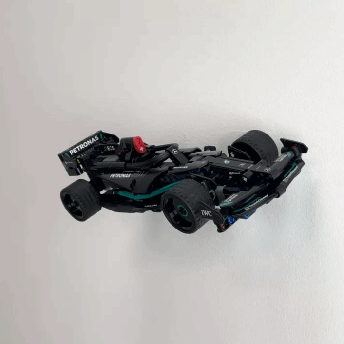 Wall display mount holding LEGO® Mercedes Speed Chaser F1 (42165) model, presenting the car at an angled position on the wall for a striking visual display.
